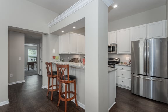 Kitchen with stainless steel appliances and a bar with wooden stools