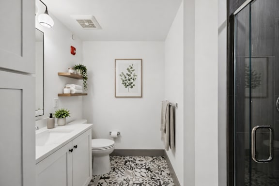 A bathroom with a toilet, sink, and a framed picture on the wall.