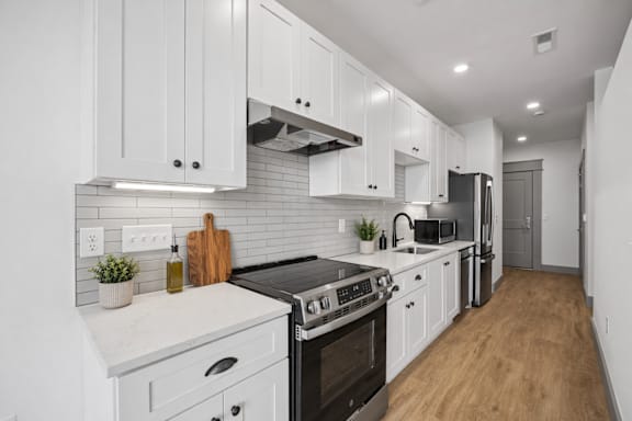 A modern kitchen with white cabinets and a black stove top oven.