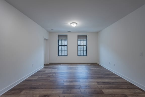 an empty living room with wood floors and two windows