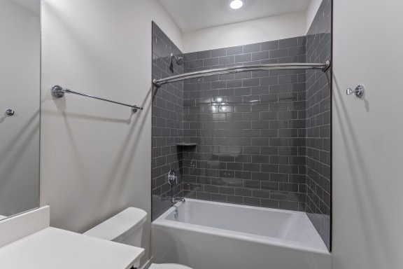 a gray and white bathroom with a tub and shower and a sink