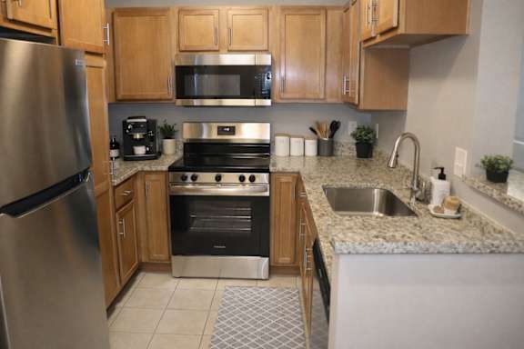 A kitchen with a stainless steel refrigerator, microwave, oven, and sink.