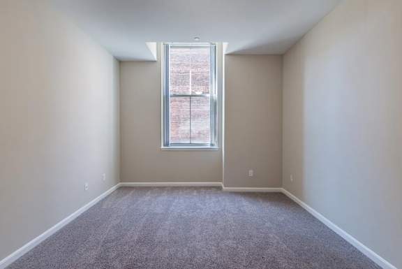 Empty carpeted bedroom with single window at Renaissance at the Power Building Apartments, Ohio