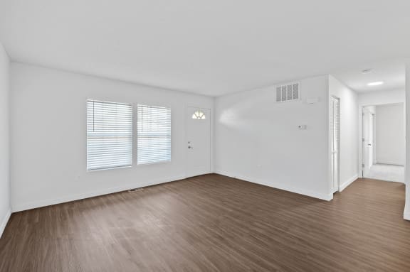 an empty living room with wood flooring and white walls