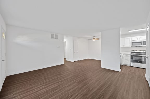 an empty living room and kitchen with white walls and wood flooring