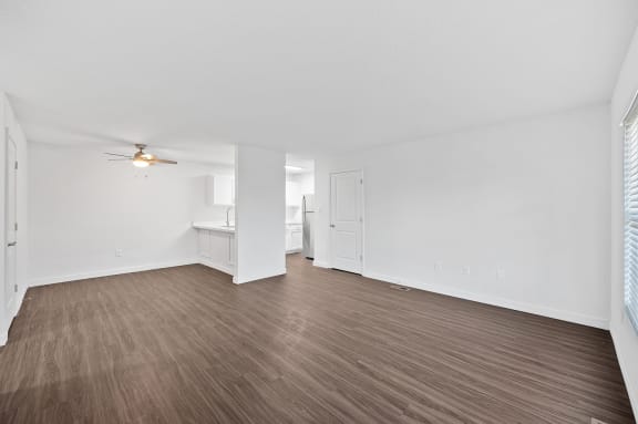 an empty living room with wood flooring and a ceiling fan