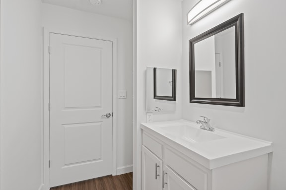 a bathroom with a sink and a mirror and a door