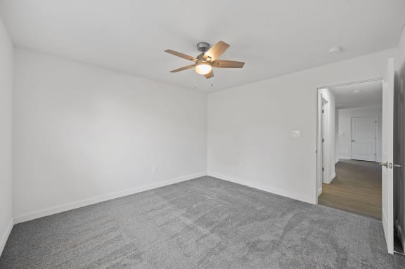 an empty living room with white walls and a ceiling fan