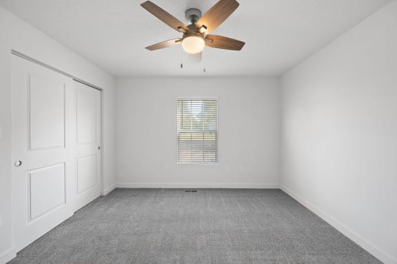 an empty room with a ceiling fan and a window
