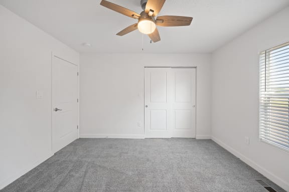 an empty bedroom with a ceiling fan and a door