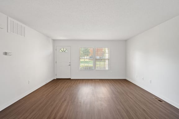 an empty living room with wood floors and white walls