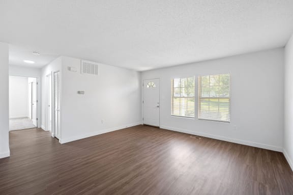 an empty living room with wood floors and white walls