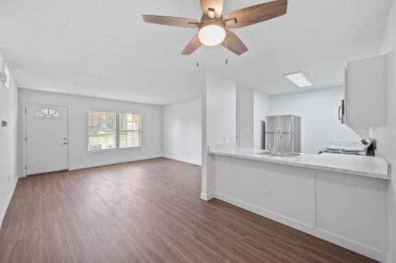 an empty living room and kitchen with a ceiling fan