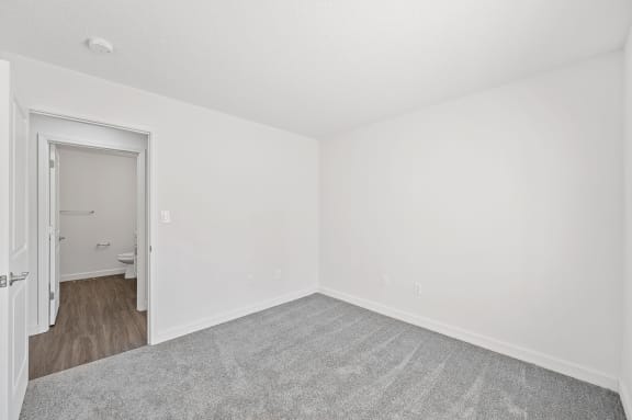 an empty room with white walls and a door to a bathroom
