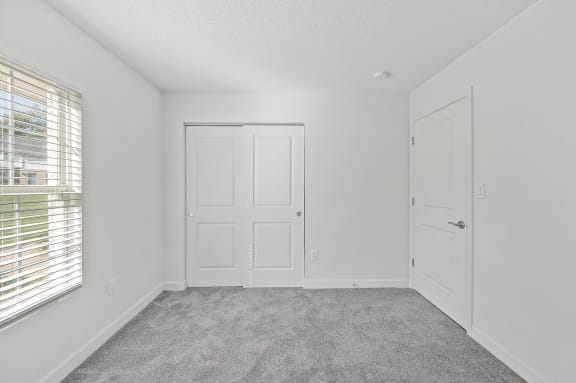 an empty bedroom with white walls and a window