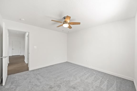 an empty living room with white walls and a ceiling fan