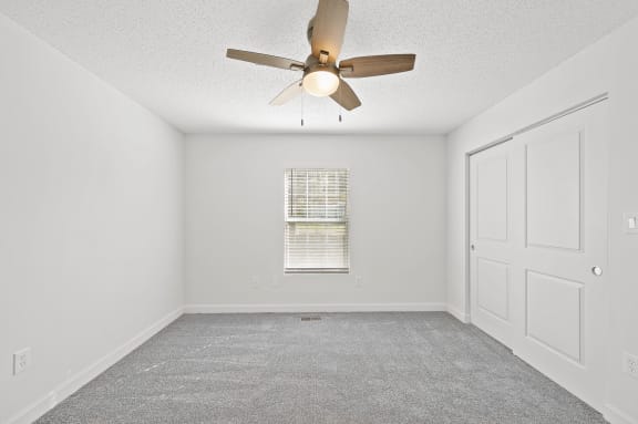 an empty room with a ceiling fan and a window
