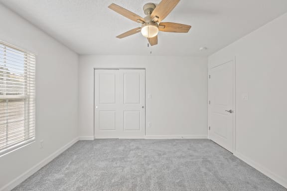 an empty room with a ceiling fan and a door