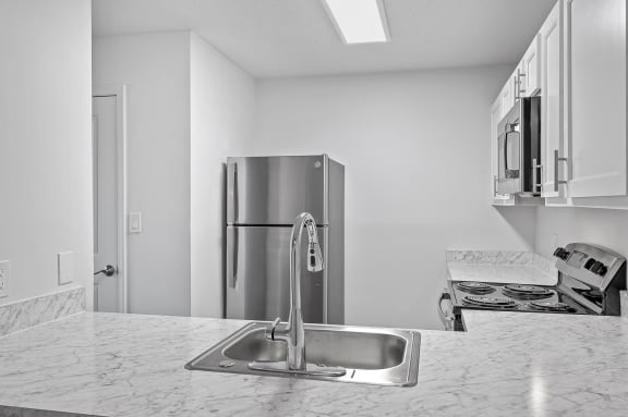 a kitchen with a sink and a stainless steel refrigerator