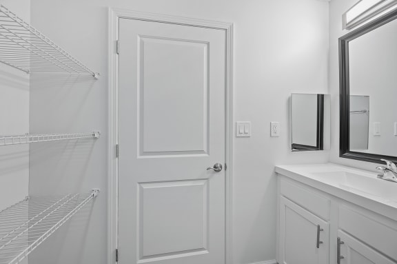 a white bathroom with a shower and a sink and a white door