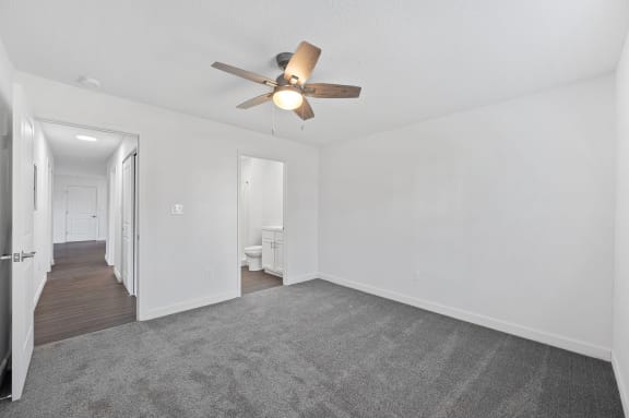 a living room with white walls and a ceiling fan