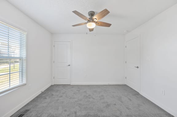 an empty room with a ceiling fan and a window