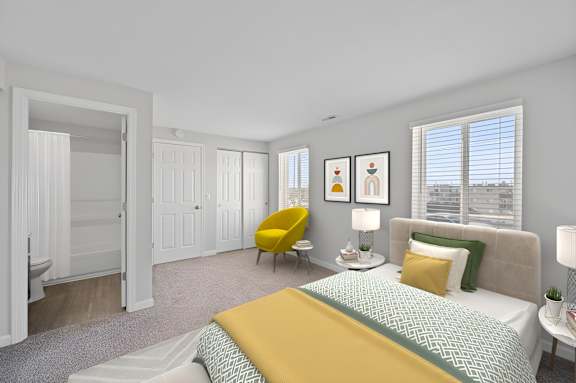 A bedroom with a bed, yellow chair, and two lamps.