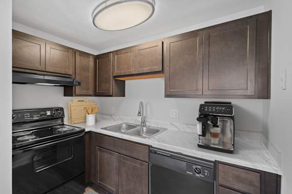 A kitchen with a black stove top oven and a black dishwasher.