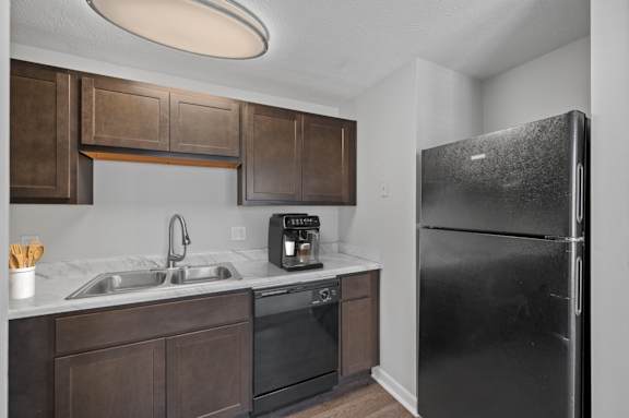 A kitchen with a black refrigerator and brown cabinets.