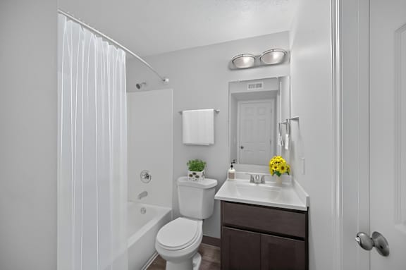 A white bathroom with a toilet, sink, and mirror. at The Apex, Ohio