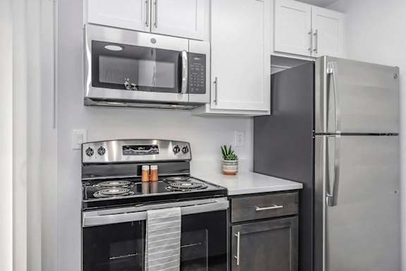 A modern kitchen with a stainless steel refrigerator, microwave, oven, and stove at Mallard Landing Apartments, Marion, 43302