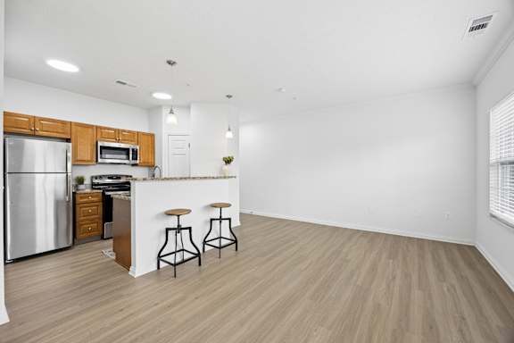 A kitchen with a refrigerator, microwave, and bar stools.