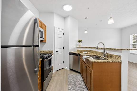 A modern kitchen with a stainless steel refrigerator and wooden cabinets.