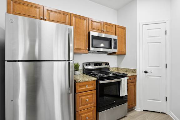 A kitchen with a refrigerator, microwave, oven, and cabinets.