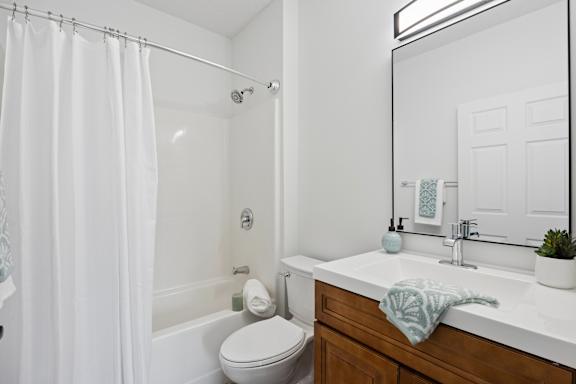 A white bathroom with a toilet, sink, and shower.