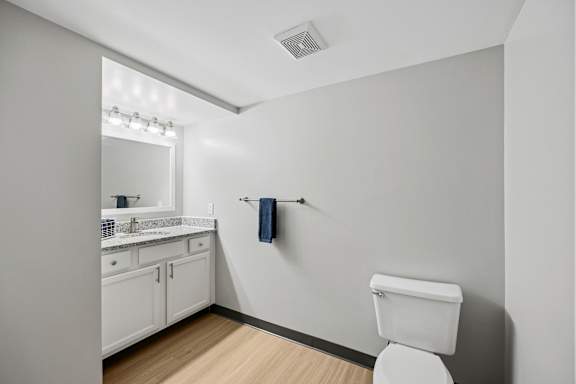 A white toilet sits in a bathroom with a white sink and a mirror.