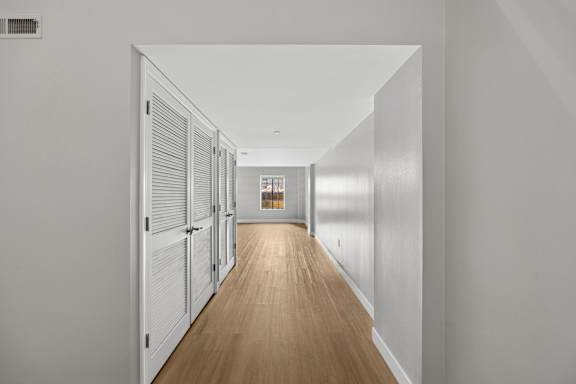 A long hallway with white walls and wood floors.