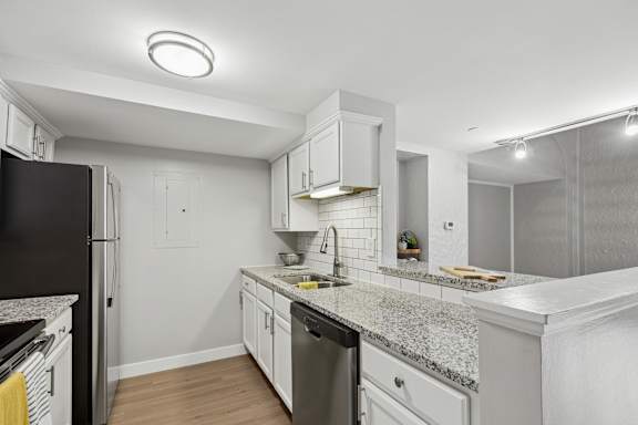 A kitchen with a black refrigerator and white cabinets.