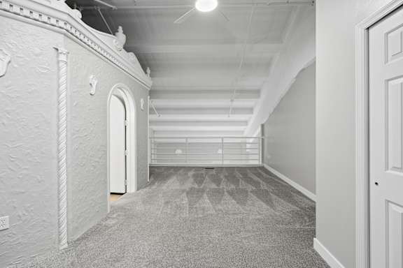 A long, narrow hallway with a carpeted floor and white walls.