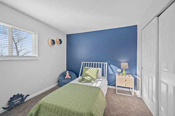 A bedroom with a bed, nightstand, and window.