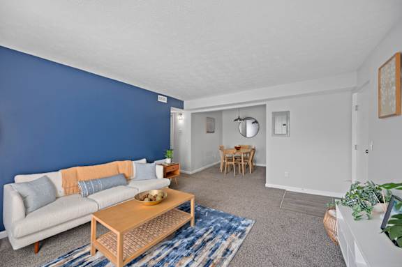 A living room with a couch, coffee table, and dining area.