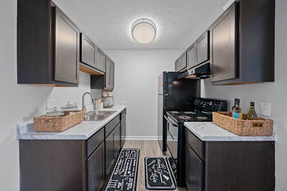 A kitchen with dark brown cabinets and a white countertop.