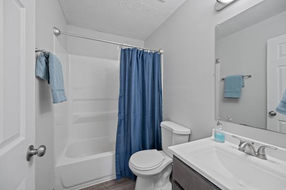 A white bathroom with a blue shower curtain.