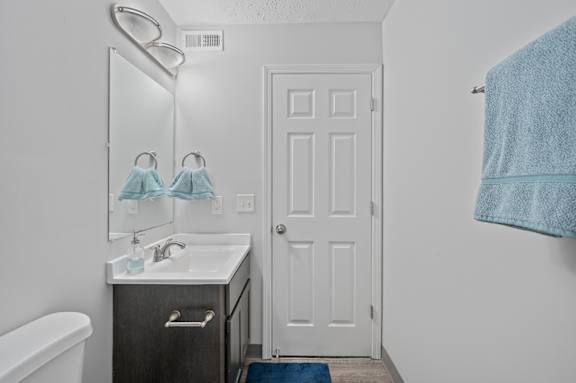 A bathroom with a white door, a white sink, and a blue rug.