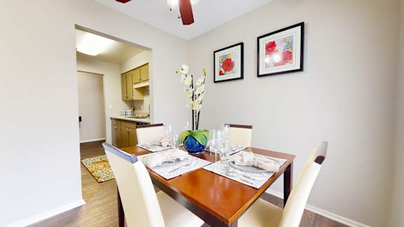 A dining room with a table set for two and a vase of flowers on the table.