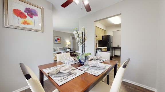 A dining room with a table set for two and a ceiling fan.