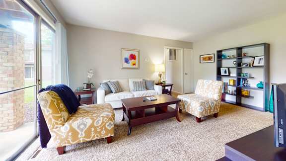 A living room with a yellow patterned chair and a white couch.