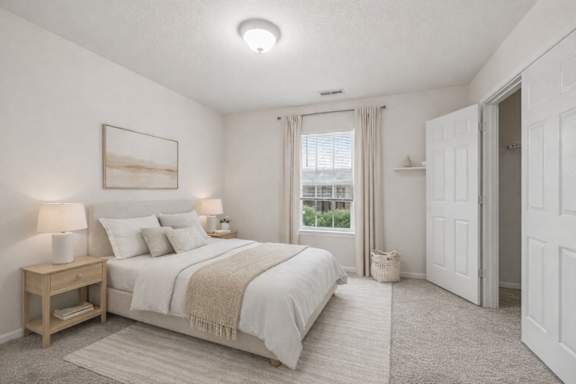 A bedroom with a large bed, two lamps, and a painting on the wall.