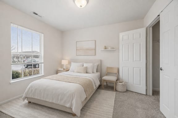 A bedroom with a large bed and a window overlooking a parking lot.