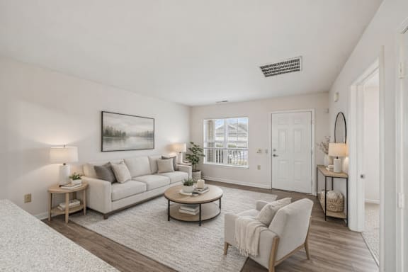 A well-lit, spacious living room with a large couch, a coffee table, and a bed.